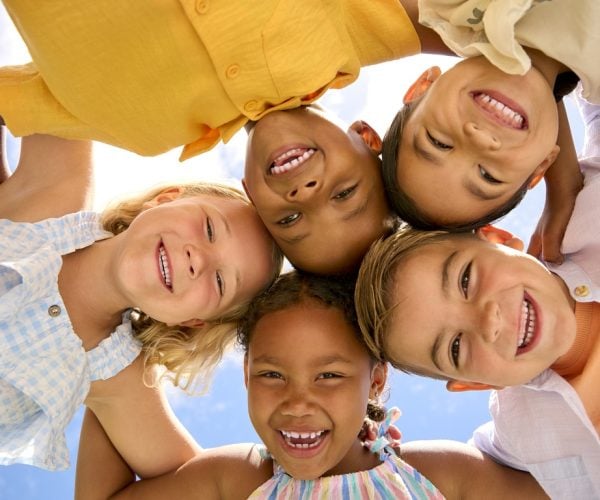 Group Of Multi-Cultural Children Friends Linking Arms Looking Down Into Camera