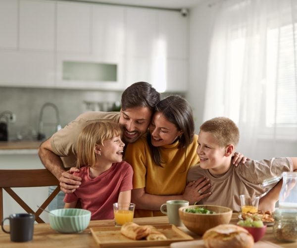 Young parents and their small kids having breakfast in dining room