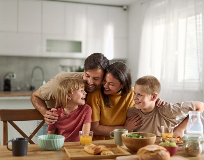 Young parents and their small kids having breakfast in dining room